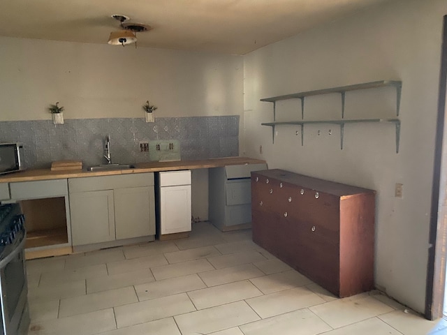 501 S Clay St, Henrietta, TX 76365 - kitchen featuring a sink, open shelves, stainless steel range with gas cooktop, and backsplash