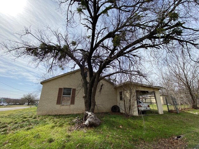501 S Clay St, Henrietta, TX 76365 - view of side of property with brick siding and a yard