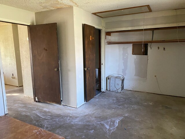 501 S Clay St, Henrietta, TX 76365 - unfurnished bedroom featuring unfinished concrete floors, attic access, and a closet