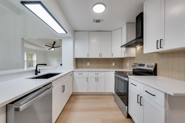 2307 Glen Forest Ln, Plano, TX 75023 - kitchen featuring stainless steel appliances, wall chimney range hood, a sink, light wood finished floors, and light countertops