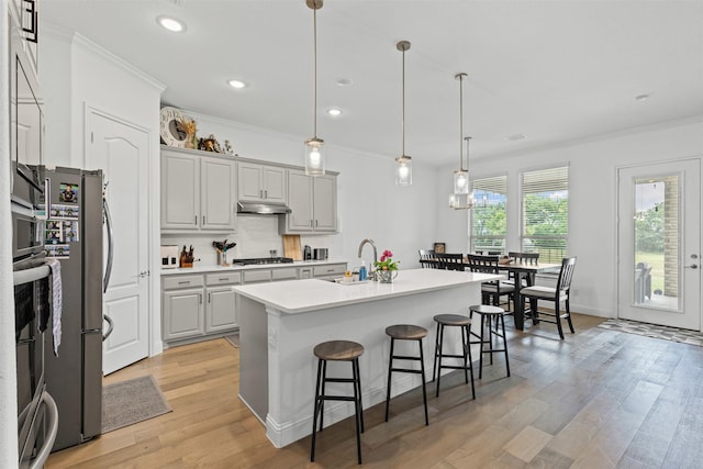 7020 Valley View Dr, Joshua, TX 76058 - kitchen featuring a sink, ornamental molding, a breakfast bar, under cabinet range hood, and light countertops