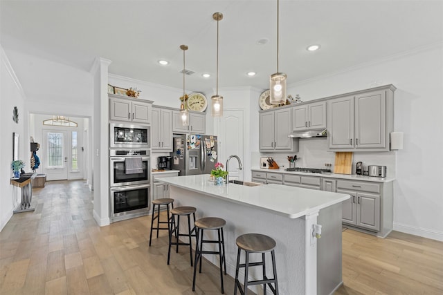 7020 Valley View Dr, Joshua, TX 76058 - kitchen with gray cabinetry, appliances with stainless steel finishes, under cabinet range hood, ornamental molding, and a breakfast bar area