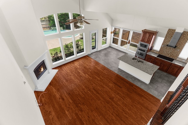 8204 Saint Clair Dr, Mckinney, TX 75071 - unfurnished living room featuring a lit fireplace, a high ceiling, a ceiling fan, and a sink