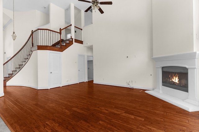 8204 Saint Clair Dr, Mckinney, TX 75071 - unfurnished living room with a ceiling fan, a towering ceiling, stairs, wood finished floors, and a tiled fireplace
