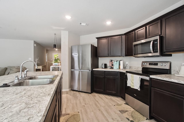 115 Rock Creek Ln, Terrell, TX 75160 - kitchen featuring appliances with stainless steel finishes, a sink, light wood-style floors, light countertops, and dark brown cabinetry