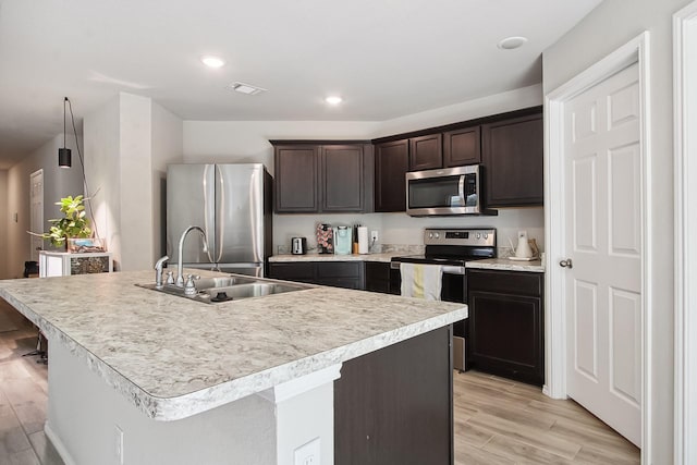 115 Rock Creek Ln, Terrell, TX 75160 - kitchen with appliances with stainless steel finishes, a sink, dark brown cabinets, light wood-style floors, and recessed lighting