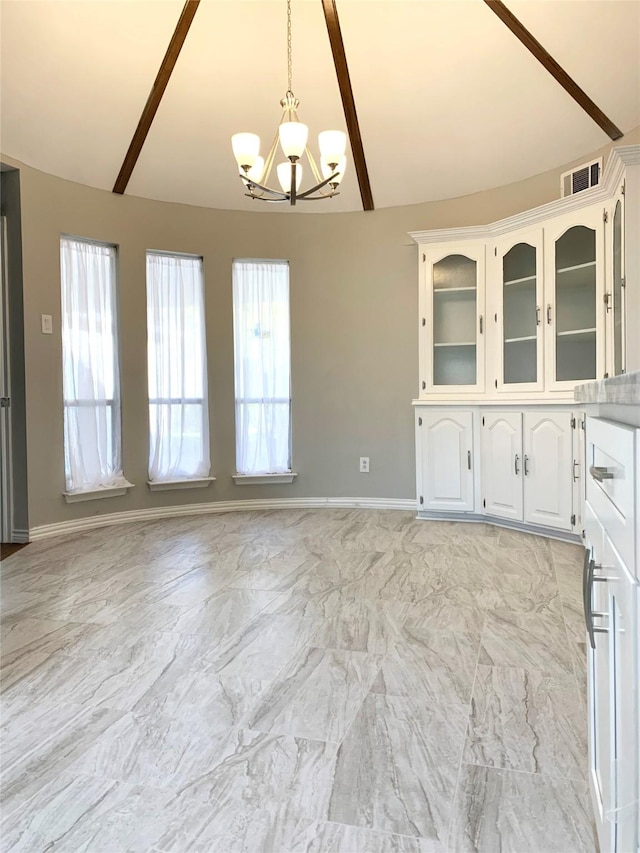 unfurnished dining area with a chandelier and baseboards