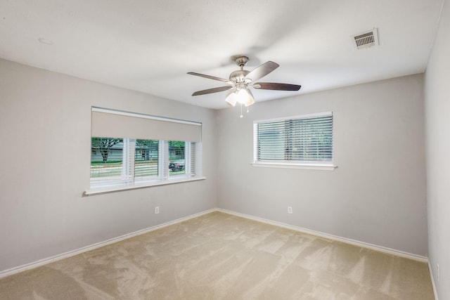 spare room featuring light colored carpet, healthy amount of natural light, ceiling fan, and baseboards