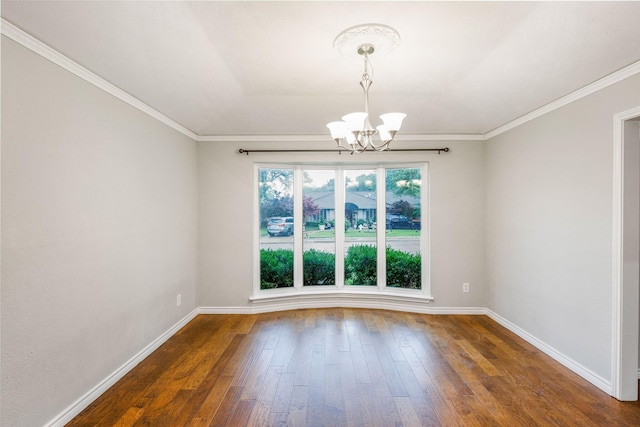 spare room featuring a chandelier, wood-type flooring, baseboards, and crown molding