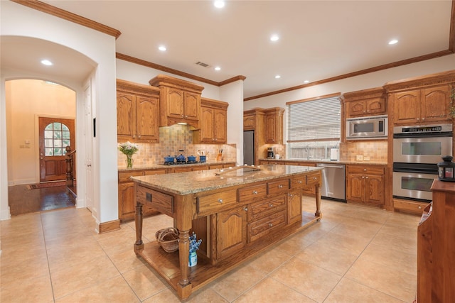 1607 Navarro Ct, Allen, TX 75013 - kitchen with appliances with stainless steel finishes, light tile patterned floors, backsplash, brown cabinets, and ornamental molding