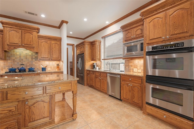 1607 Navarro Ct, Allen, TX 75013 - kitchen featuring stainless steel appliances, light stone counters, crown molding, backsplash, and brown cabinets
