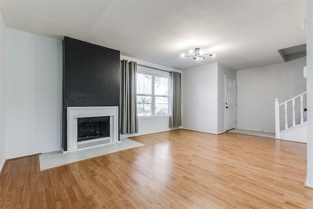 323 Towne House Ln, Richardson, TX 75081 - unfurnished living room featuring wood finished floors, a chandelier, stairs, and a fireplace