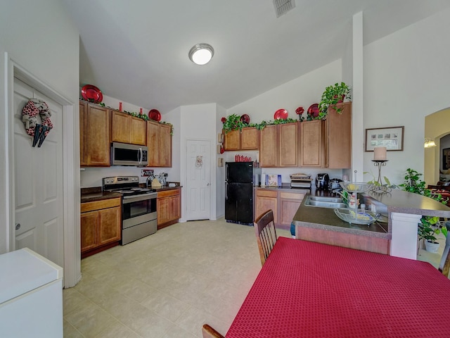 3929 Bonita Springs Dr, Fort Worth, TX 76123 - kitchen featuring stainless steel appliances, brown cabinetry, dark countertops, and a peninsula