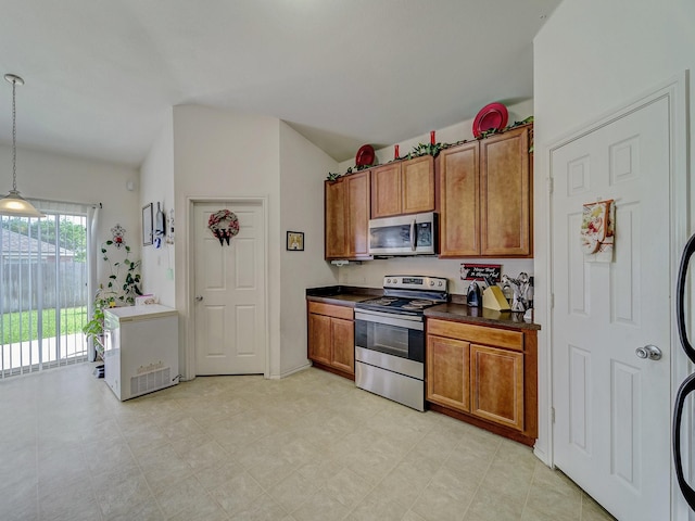 3929 Bonita Springs Dr, Fort Worth, TX 76123 - kitchen featuring stainless steel appliances, brown cabinetry, lofted ceiling, dark countertops, and decorative light fixtures