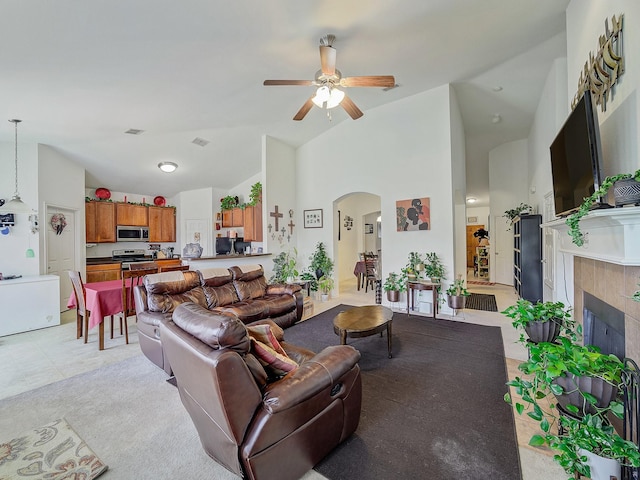 3929 Bonita Springs Dr, Fort Worth, TX 76123 - living area featuring arched walkways, ceiling fan, a tiled fireplace, and high vaulted ceiling