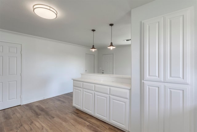 943 Lone Star Rd, Whitesboro, TX 76273 - kitchen featuring crown molding, decorative light fixtures, white cabinets, light wood-style flooring, and a peninsula