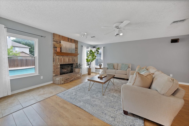 2200 Bantry Ln, Arlington, TX 76002 - living room with a textured ceiling, wood finished floors, ceiling fan, a brick fireplace, and baseboards