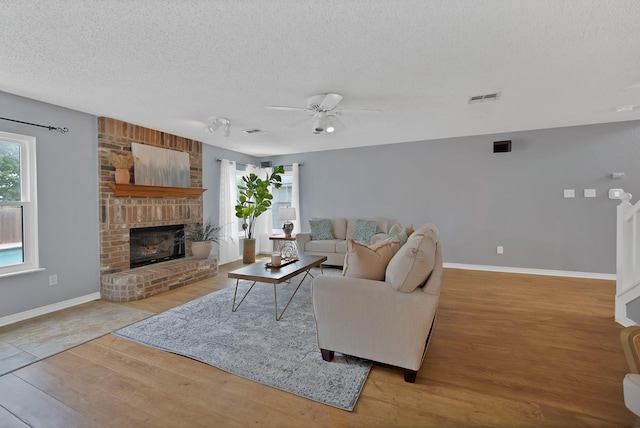 2200 Bantry Ln, Arlington, TX 76002 - living area featuring wood finished floors, a textured ceiling, a fireplace, ceiling fan, and baseboards