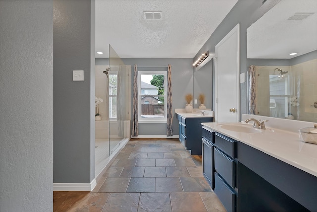 2200 Bantry Ln, Arlington, TX 76002 - bathroom featuring a stall shower, baseboards, a textured ceiling, two vanities, and a textured wall