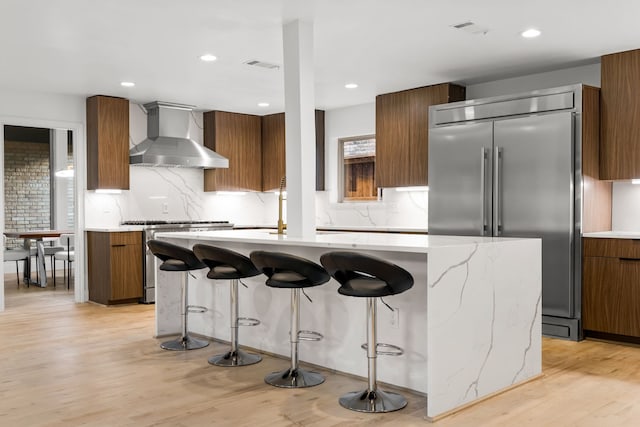 9415 Hill View Dr, Dallas, TX 75231 - kitchen with stainless steel appliances, wall chimney range hood, modern cabinets, brown cabinets, and recessed lighting