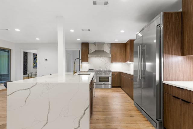9415 Hill View Dr, Dallas, TX 75231 - kitchen with wall chimney range hood, premium appliances, a sink, light wood-type flooring, and modern cabinets