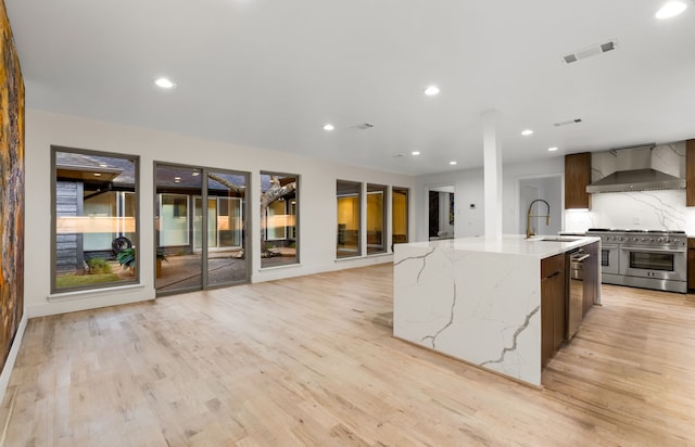 9415 Hill View Dr, Dallas, TX 75231 - kitchen with wall chimney range hood, appliances with stainless steel finishes, light wood-style flooring, a sink, and recessed lighting