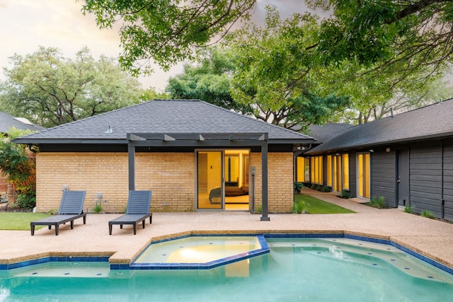 9415 Hill View Dr, Dallas, TX 75231 - rear view of house with brick siding, a patio, a shingled roof, and a pool with connected hot tub