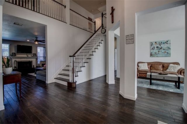 2505 Wilma Ln, Plano, TX 75074 - stairway featuring hardwood / wood-style floors, a ceiling fan, a towering ceiling, and a fireplace
