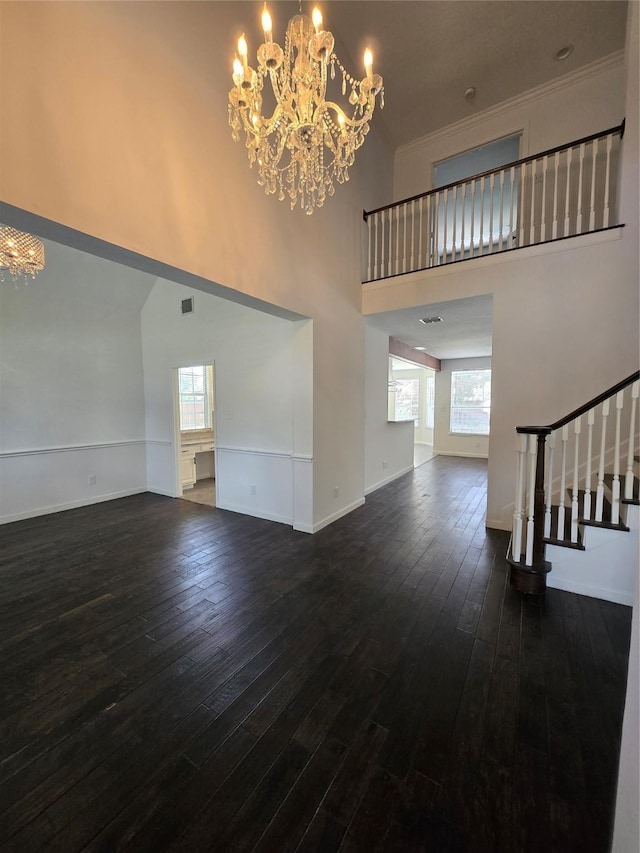 2505 Wilma Ln, Plano, TX 75074 - unfurnished living room with a towering ceiling, a chandelier, dark wood-style flooring, stairway, and ornamental molding