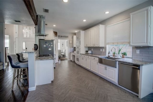 2505 Wilma Ln, Plano, TX 75074 - kitchen with stainless steel appliances, wall chimney exhaust hood, white cabinetry, a breakfast bar area, and recessed lighting