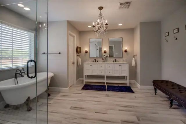 2505 Wilma Ln, Plano, TX 75074 - bathroom with double vanity, a chandelier, a freestanding tub, wood finished floors, and recessed lighting