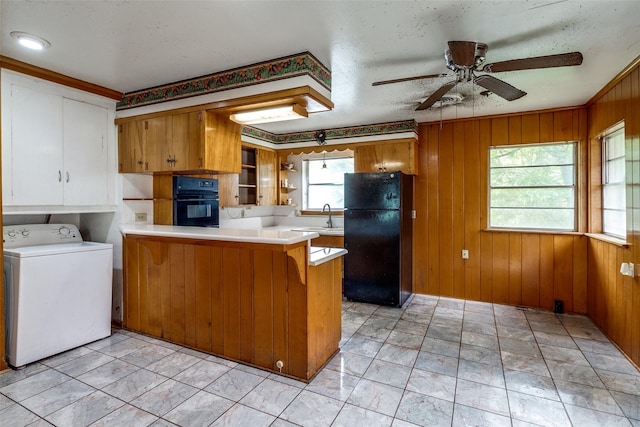 1231 Arizona Ave, Dallas, TX 75216 - kitchen featuring black appliances, washer / dryer, a peninsula, brown cabinets, and wooden walls