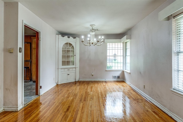 1231 Arizona Ave, Dallas, TX 75216 - unfurnished dining area with a chandelier, light wood-style floors, and baseboards