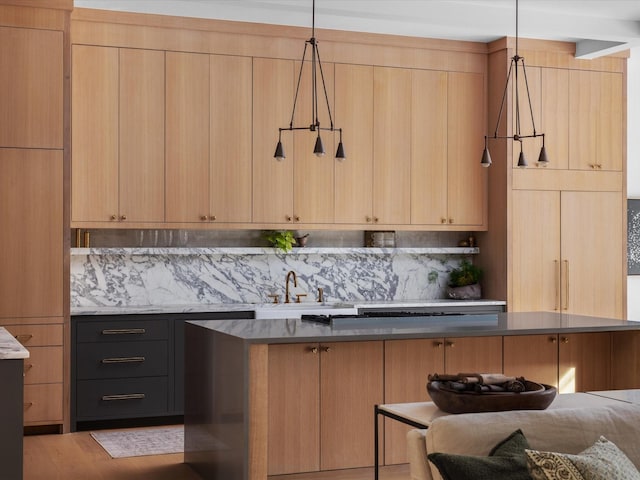 kitchen featuring light brown cabinetry, a sink, decorative backsplash, pendant lighting, and modern cabinets
