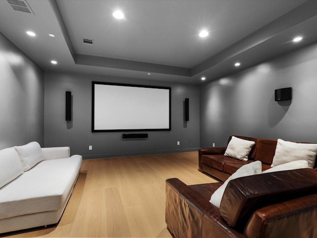 home theater featuring light wood-type flooring, a raised ceiling, recessed lighting, and baseboards