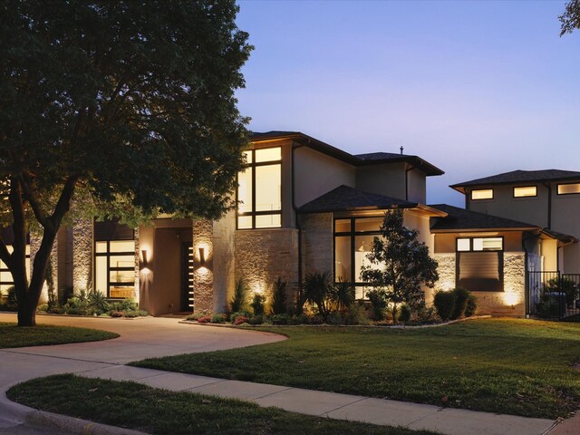 view of front of property featuring stone siding, stucco siding, and a front lawn