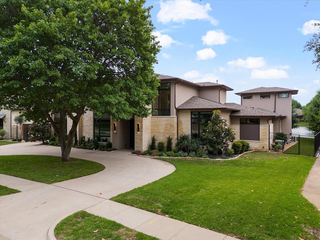 view of front of home featuring stucco siding, stone siding, and curved driveway