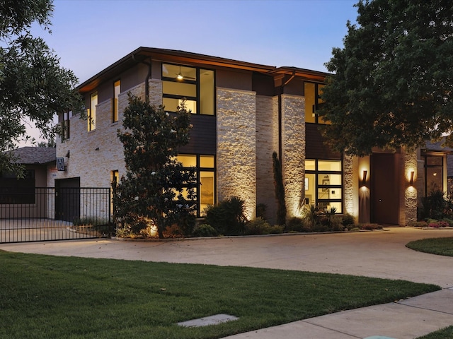 view of front of property featuring stone siding, driveway, a gate, and a garage