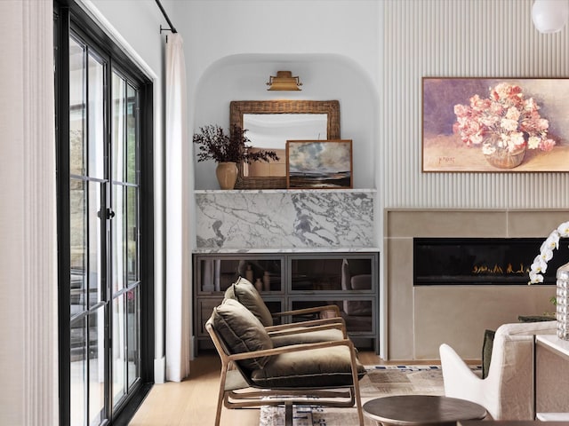 living area with a glass covered fireplace, plenty of natural light, and wood finished floors