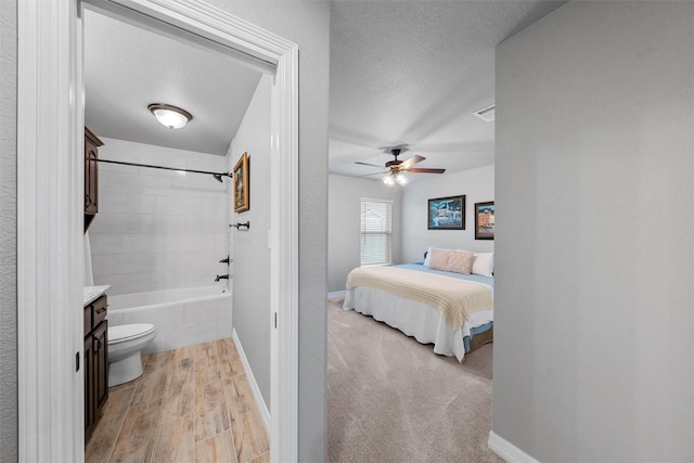 full bathroom with a ceiling fan, toilet, a textured ceiling, vanity, and baseboards