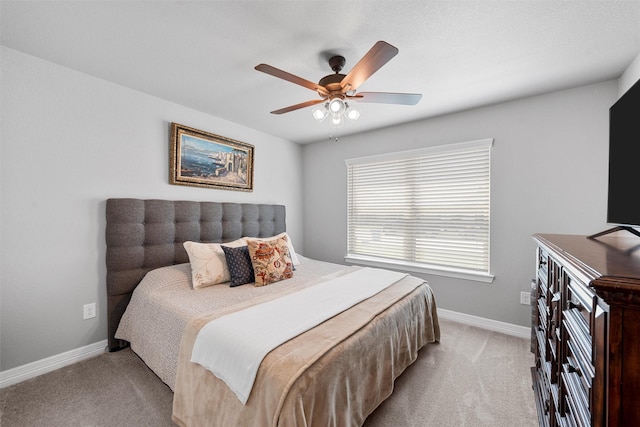 bedroom featuring light colored carpet, baseboards, and a ceiling fan