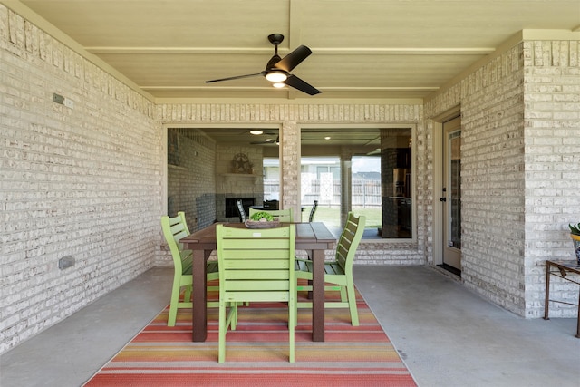 view of patio with a multi sided fireplace, ceiling fan, and outdoor dining area