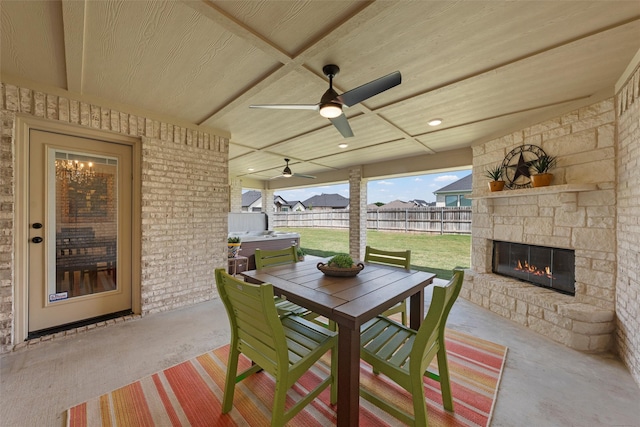 view of patio featuring an outdoor stone fireplace, outdoor dining area, and ceiling fan