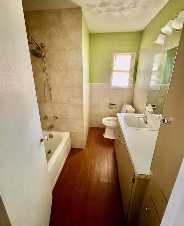 2142 Woodard St, Abilene, TX 79605 - bathroom featuring tile walls, vanity, wood finished floors, toilet, and tub / shower combination