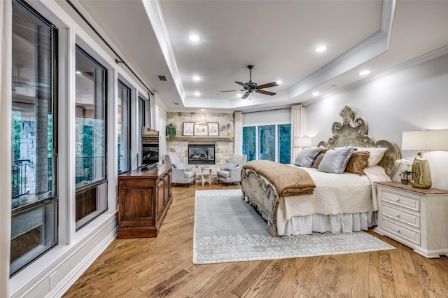 6645 Whispering Woods Ct, Plano, TX 75024 - bedroom featuring a tray ceiling, crown molding, a fireplace, light wood-type flooring, and recessed lighting