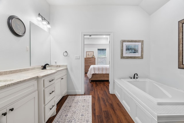 full bathroom featuring wood finished floors, vanity, connected bathroom, a bath, and baseboards