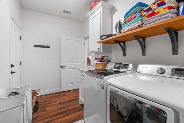 clothes washing area with cabinet space, washing machine and clothes dryer, dark wood-style floors, and baseboards