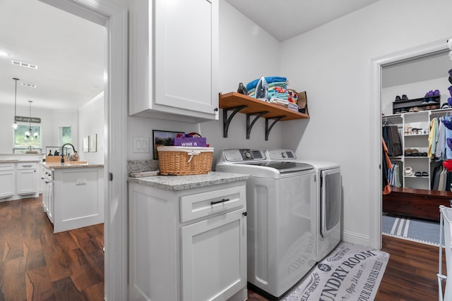 laundry area with dark wood finished floors, washing machine and clothes dryer, cabinet space, and baseboards