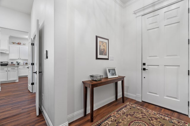 foyer featuring dark wood-style floors, crown molding, and baseboards