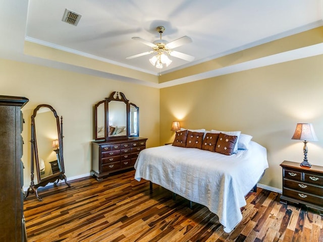 bedroom with a raised ceiling, wood finished floors, ornamental molding, baseboards, and ceiling fan